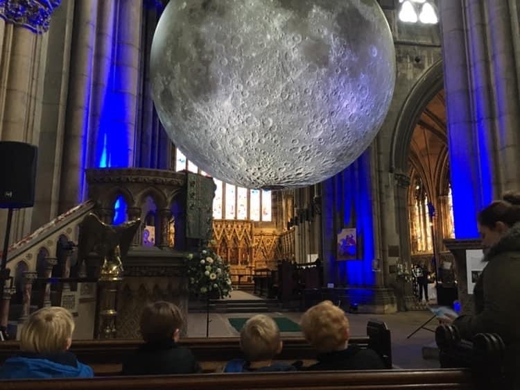 Inside of a church with a large moon hanging