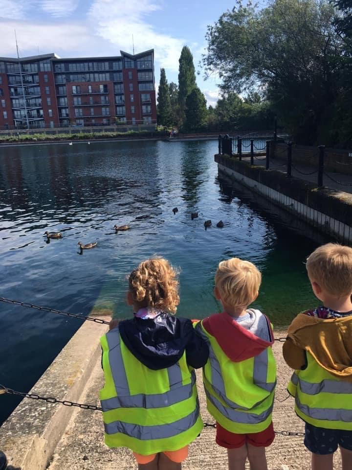 Three children looking a ducks in a lake